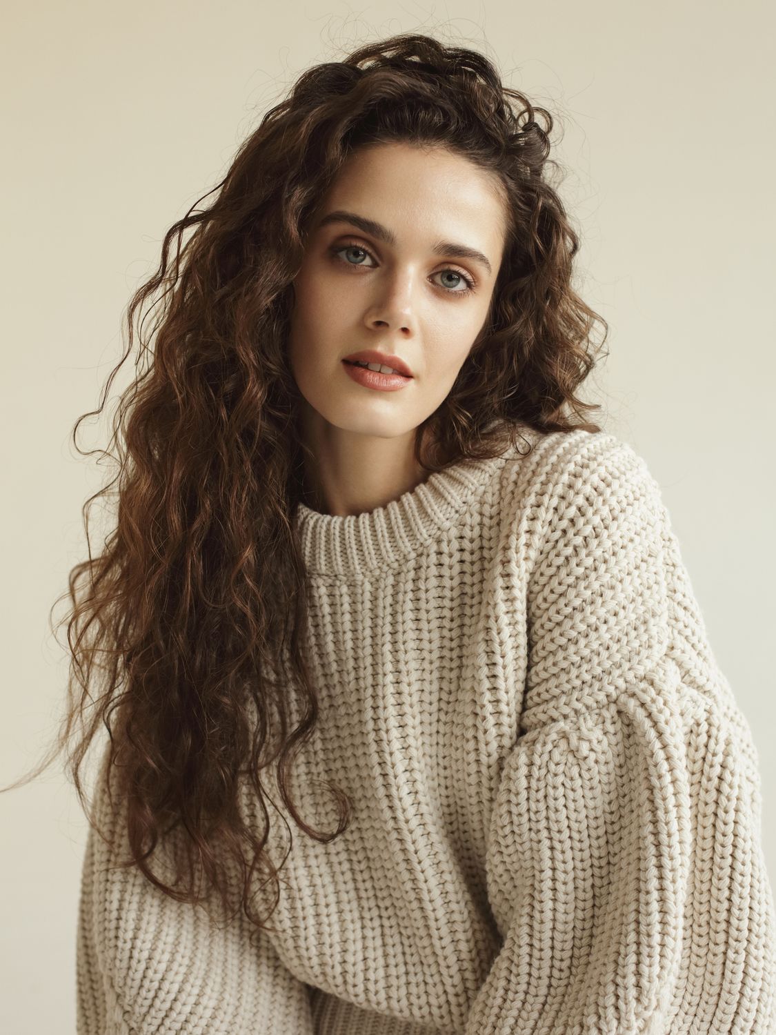 Woman with curly hair wearing a knit sweater.