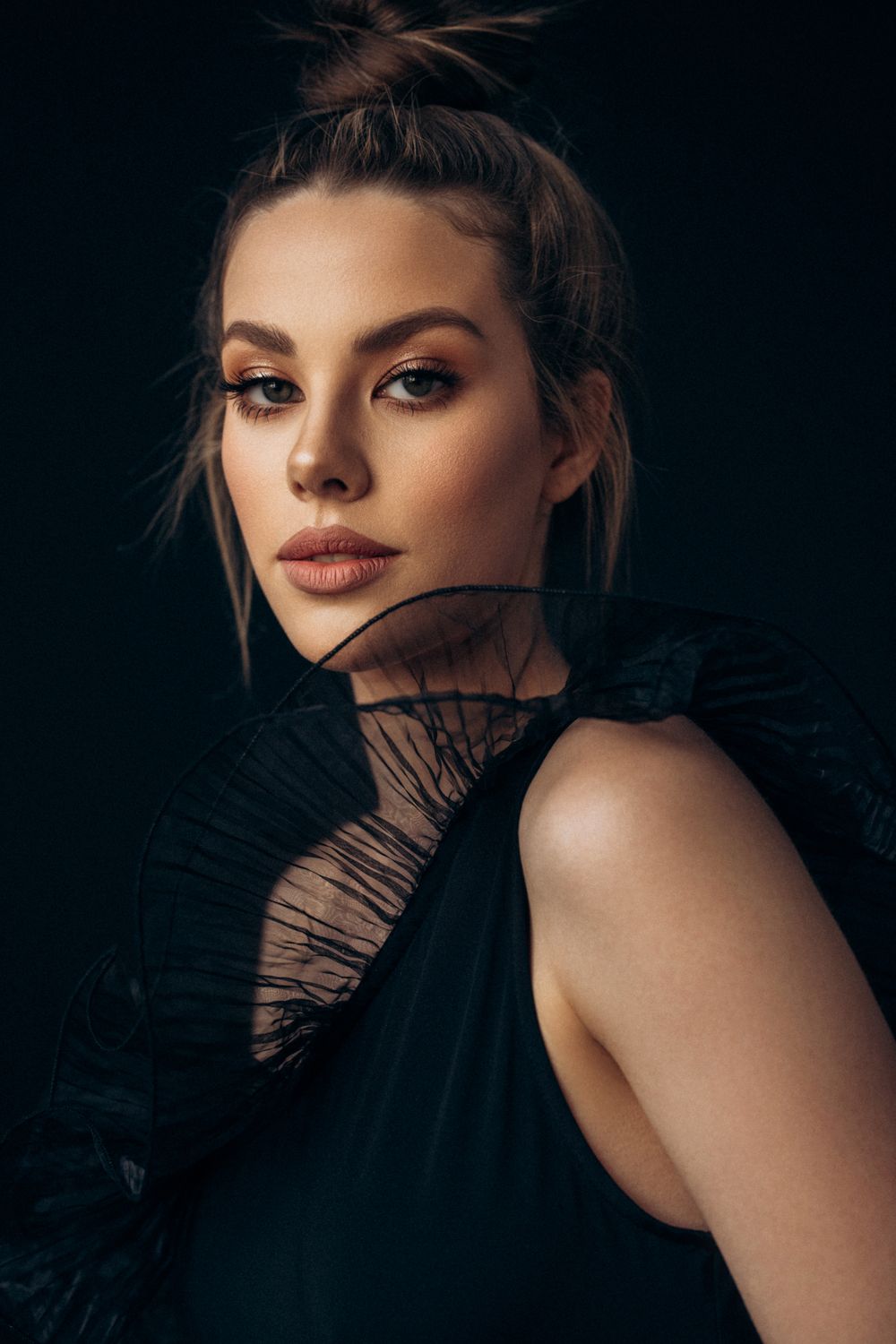 Model with elegant hairstyle and dramatic attire.