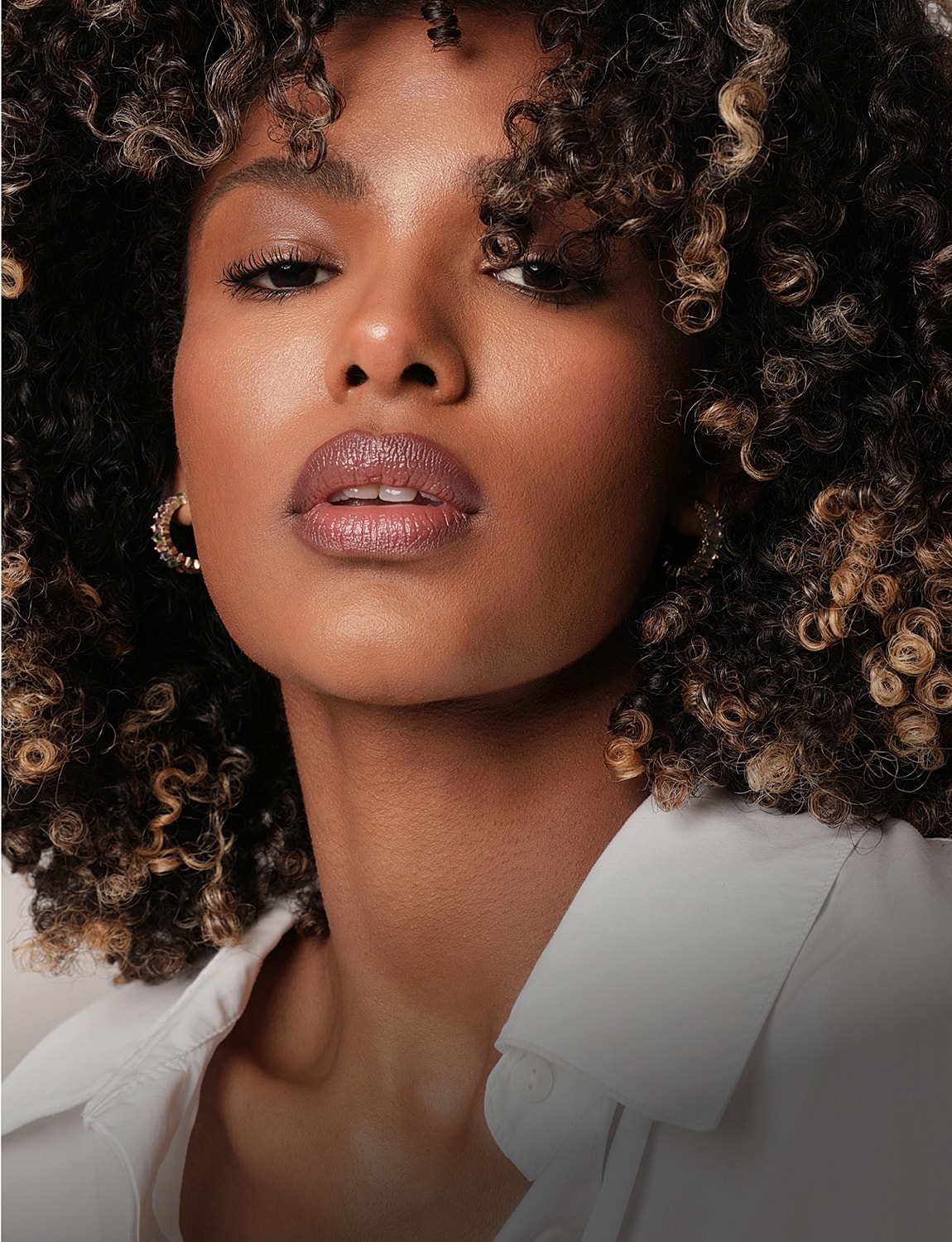Woman with curly hair in white shirt.